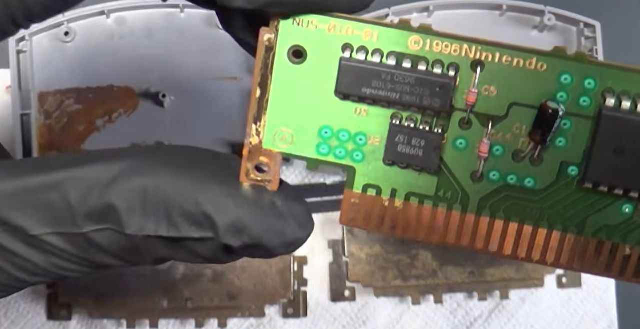 打开外壳后的 N64 卡带 PCB，金属屏蔽罩锈迹斑斑