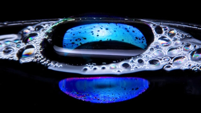 Two glowing colored bubbles against a dark background, evoking the concept of two origins
