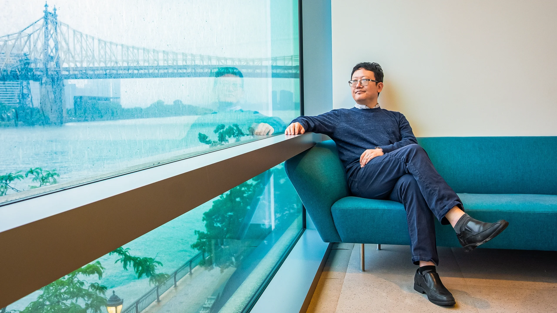 曹骏跃坐在蓝色沙发上望向窗外